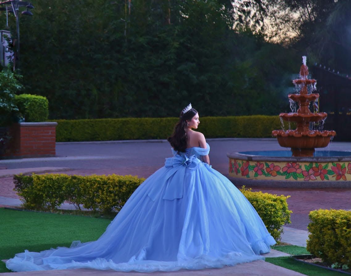 Quinceañera con vestido azul junto a la fuente de cantera al atardecer